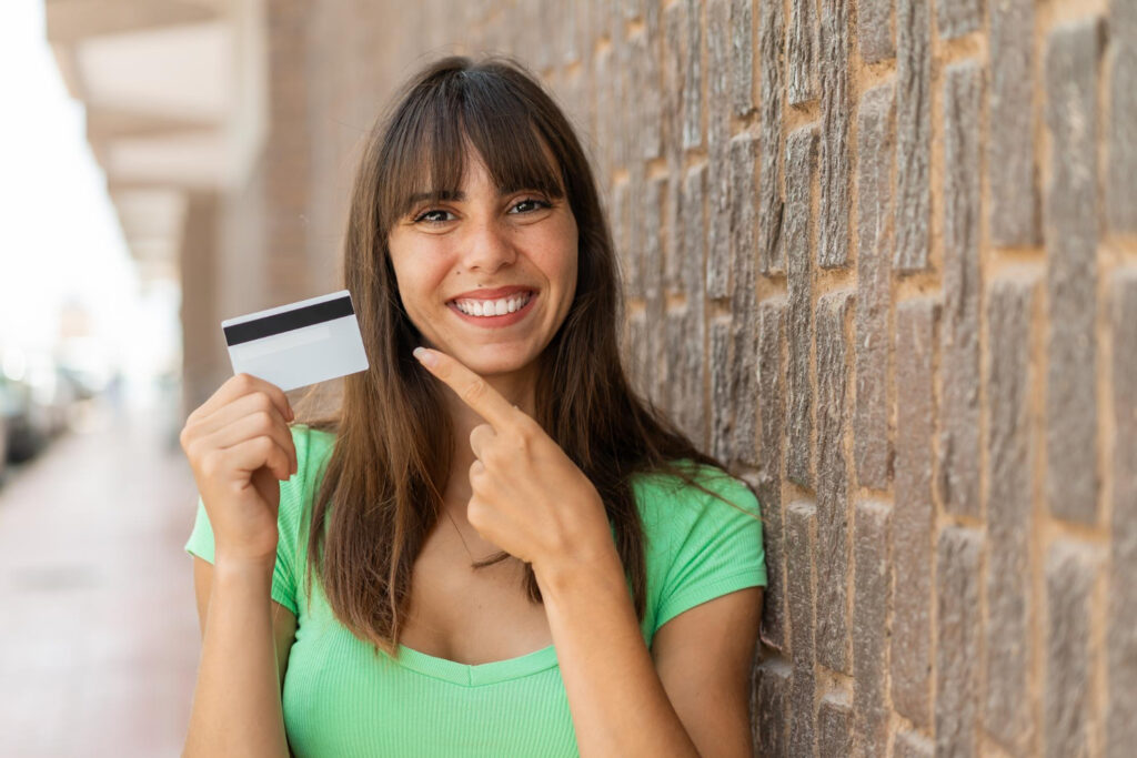 Pessoa olhando para a câmera segurando um cartão de crédito, representando uso consciente